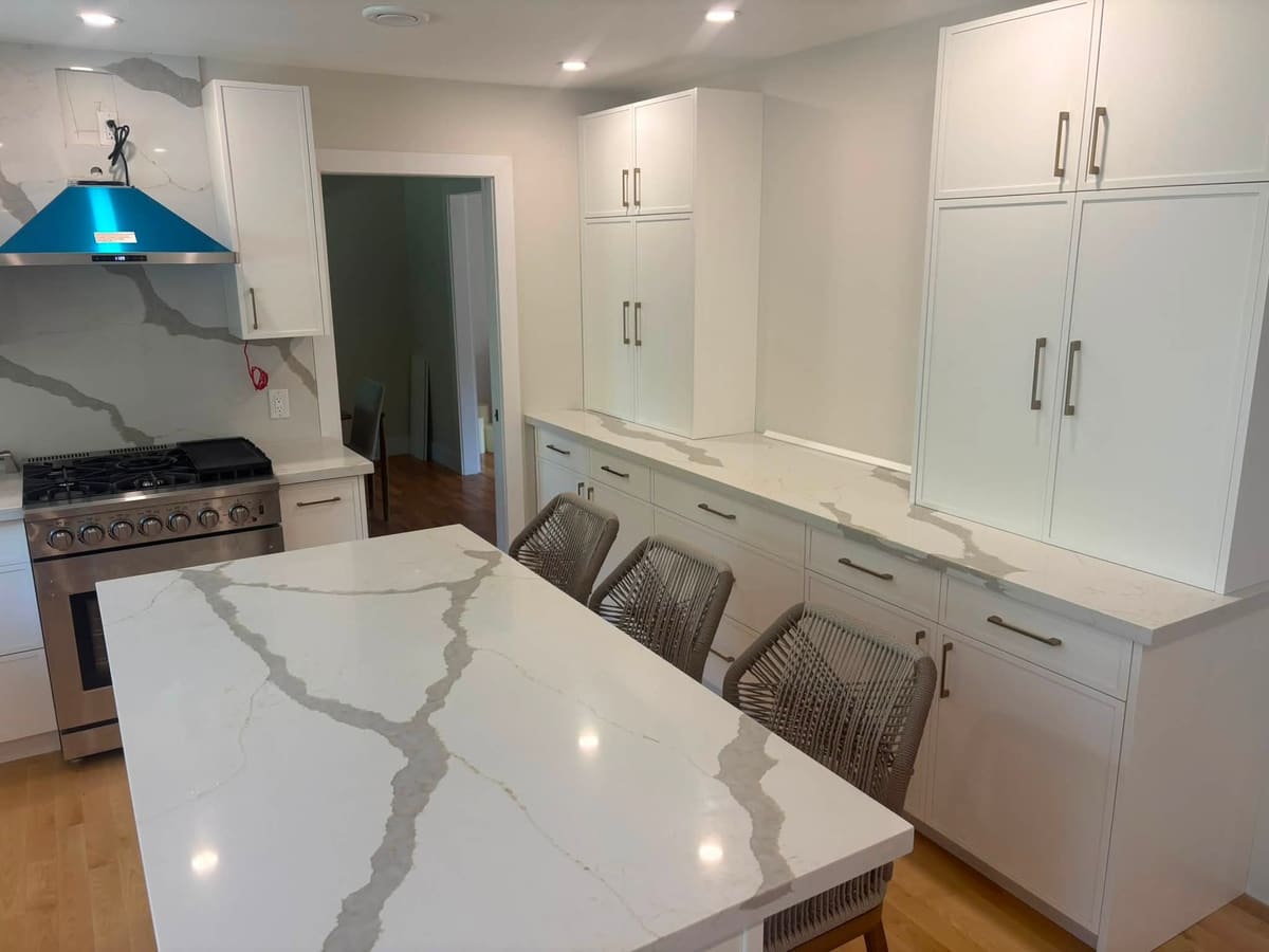 Calacatta-pattern quartz island with waterfall end and matching backsplash