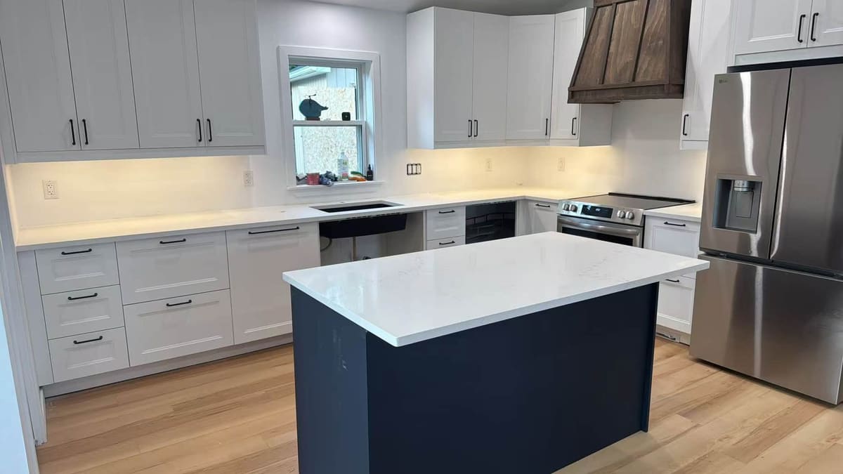 Navy island topped with white quartz beside pale grey cabinets