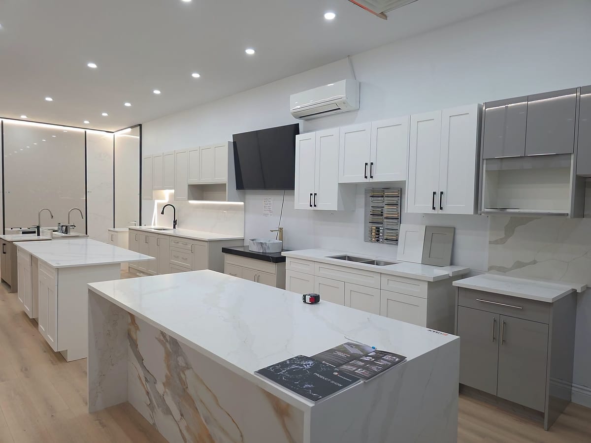 Kitchen islands in calacatta quartz and gold-veined marble with waterfall edges, on display in the Dartmouth showroom
